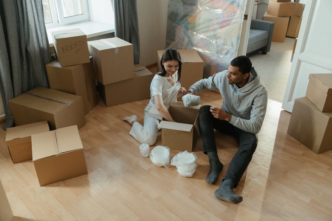 Young couple unpacking boxes in their new apartment, settling into their home.